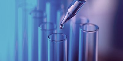 A pipette dropping liquid into a glass tube.
