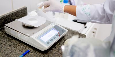 Pharmacist weights sample on a precision balance