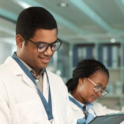 Shot of a young scientist writing notes while working alongside a colleague in a lab