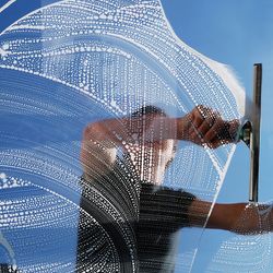 Window cleaner cleaning a window on a sunny day